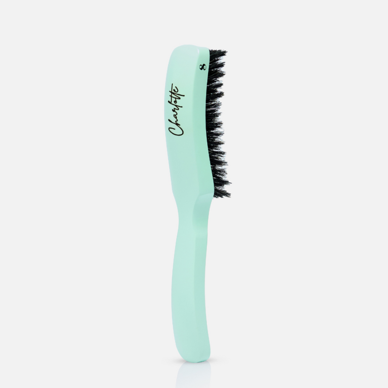 A turquoise hairbrush with the text 'Charlotte' engraved on the handle.