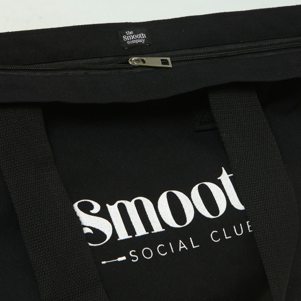 Black tote bag with 'Smoot Social Club' logo and 'The Smooth Company' label.