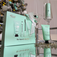 Minibar giftset on a reflective surface with a festive background.